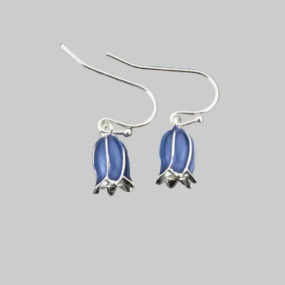 Silver earrings with blue oval stones on a gray stone background