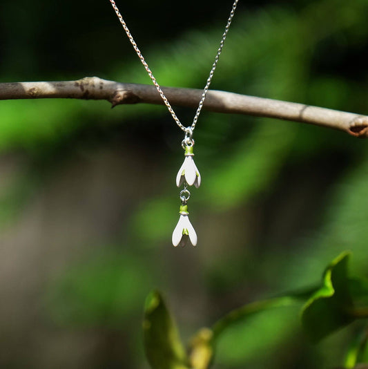 Necklace with a floral pendant on a branch against a natural background