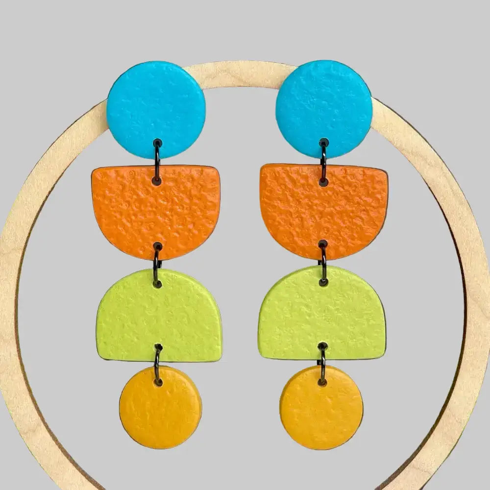 Colorful earrings with blue, orange, green, and yellow circular shapes on a gray background.