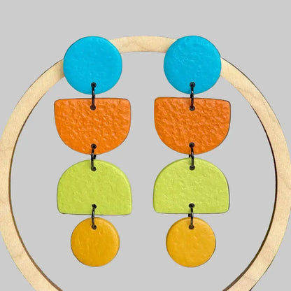 Colorful earrings with blue, orange, green, and yellow circular shapes on a gray background.