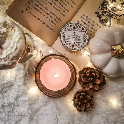 Candle, mug with hot chocolate, and decorative items on a marble surface with string lights.