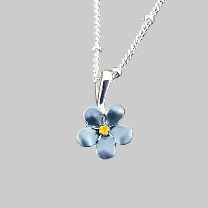 Silver necklace with a blue flower pendant on a gray stone background