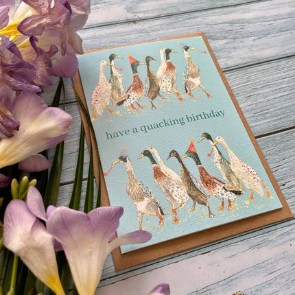 Birthday card with ducks design and flowers on a wooden surface