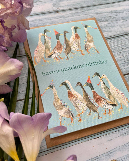 Birthday card with ducks design and flowers on a wooden surface