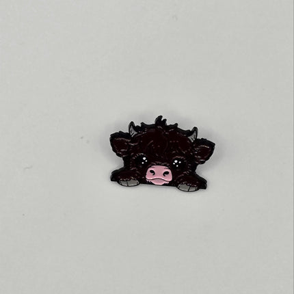 Black cow pin badge on a light gray background