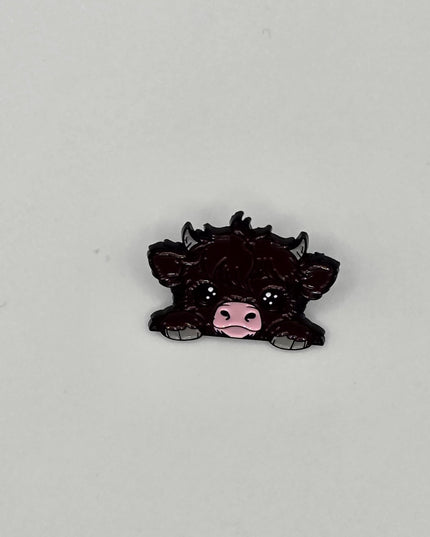 Black cow pin badge on a light gray background