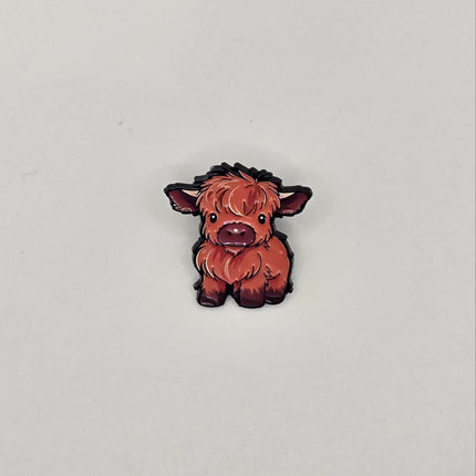 Small brown and black cow pin on a light gray background