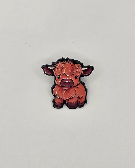 Small brown and black cow pin on a light gray background