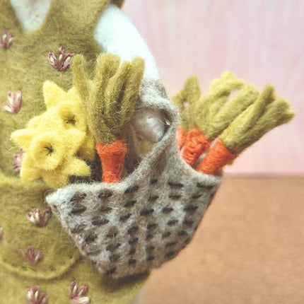 Handmade felted pouch with flowers and carrots against a pink background