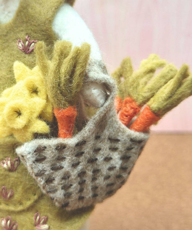 Handmade felted pouch with flowers and carrots against a pink background