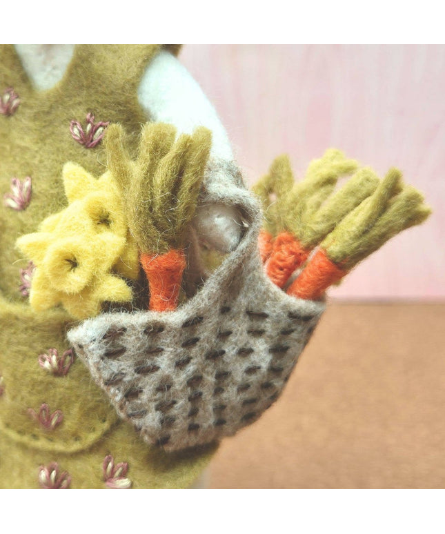 Handmade felted pouch with flowers and carrots against a pink background