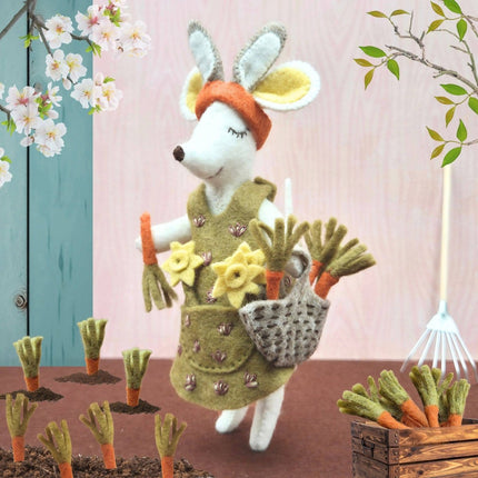 Toy rabbit in a garden setting with flowers and tools