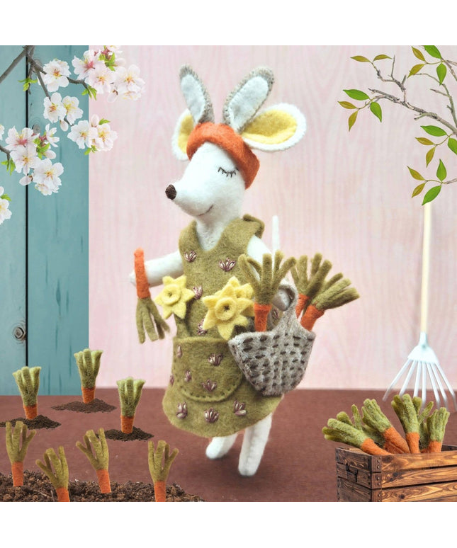 Toy rabbit in a garden setting with flowers and tools