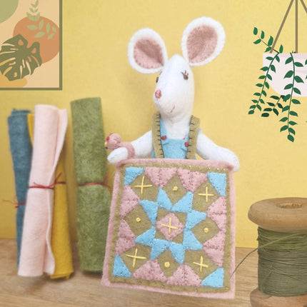 Stuffed mouse toy with a quilt on a yellow background