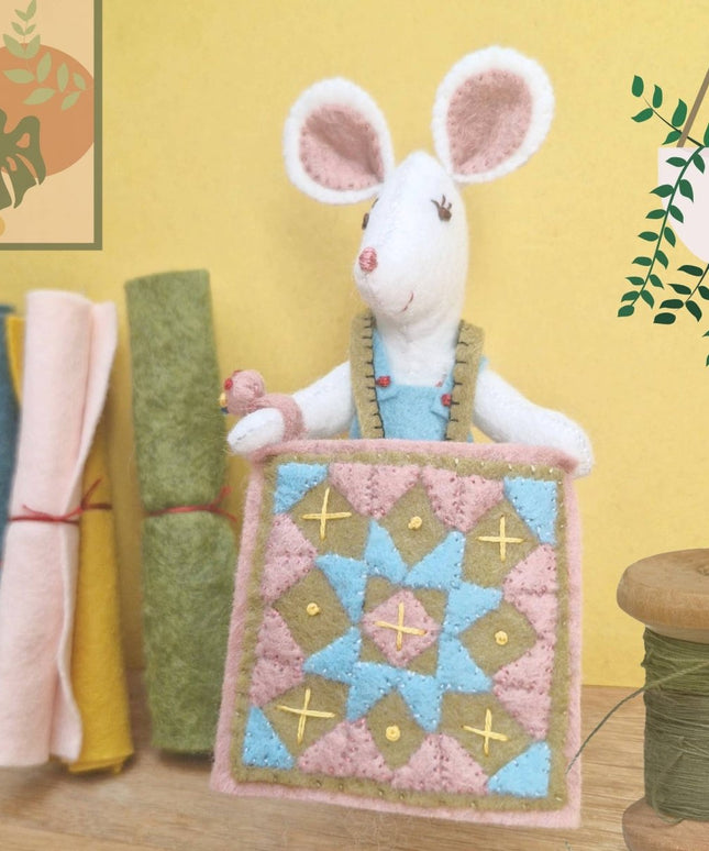 Stuffed mouse toy with a quilt on a yellow background