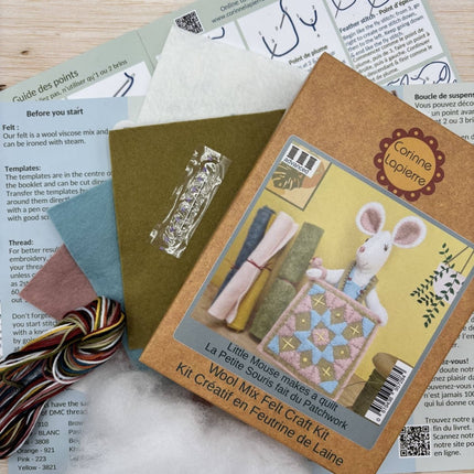 A Little Mouse makes a quilt Wool Mix Felt Craft Kit package with a multicolor striped yarn bundle, laid over printed templates and instruction sheets.