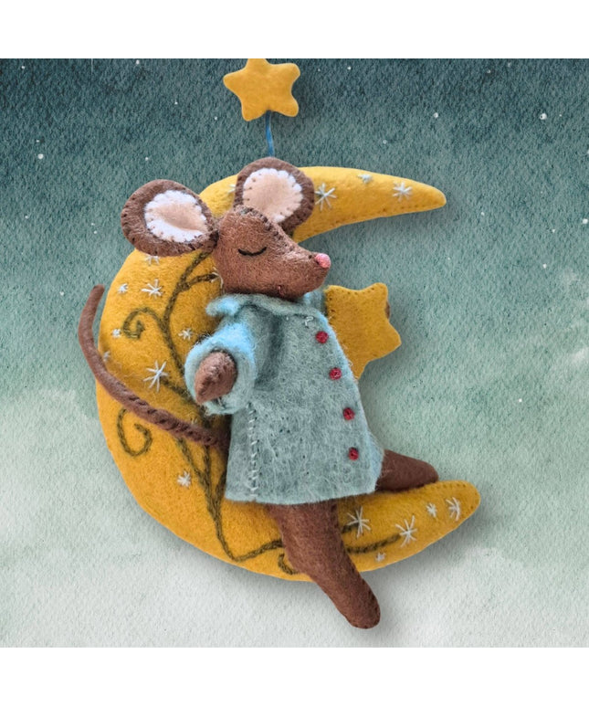A felt mouse wearing a light blue coat with red buttons, resting on a yellow crescent moon and star decoration against a soft green-blue textured background.