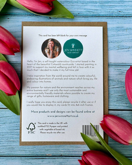Card with text and a logo surrounded by pink tulips on a wooden surface