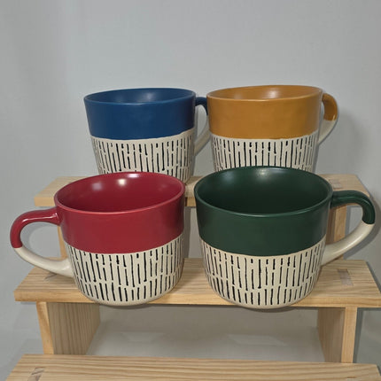 Four ceramic mugs in mustard yellow, dark green, blue, and red