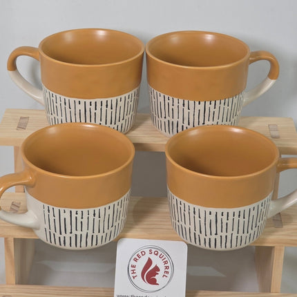 Four ceramic mugs with tan interiors and white exteriors featuring black horizontal stripes.