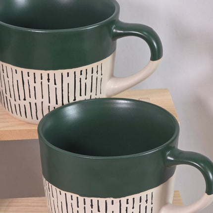 Two ceramic mugs with dark green interiors and handles, and cream-colored exteriors featuring a black dash pattern.