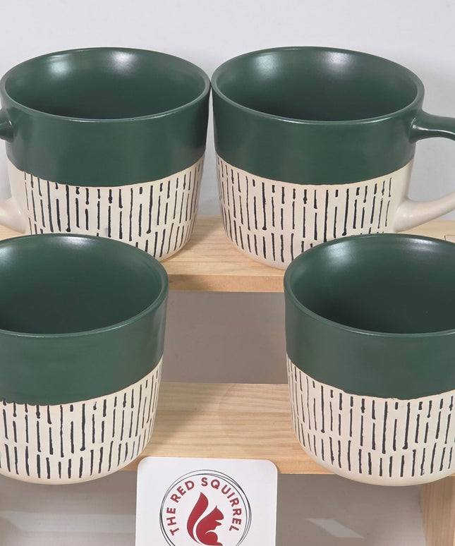 Four ceramic mugs with dark green interiors and handles, paired with cream-colored exteriors featuring a black dash pattern.