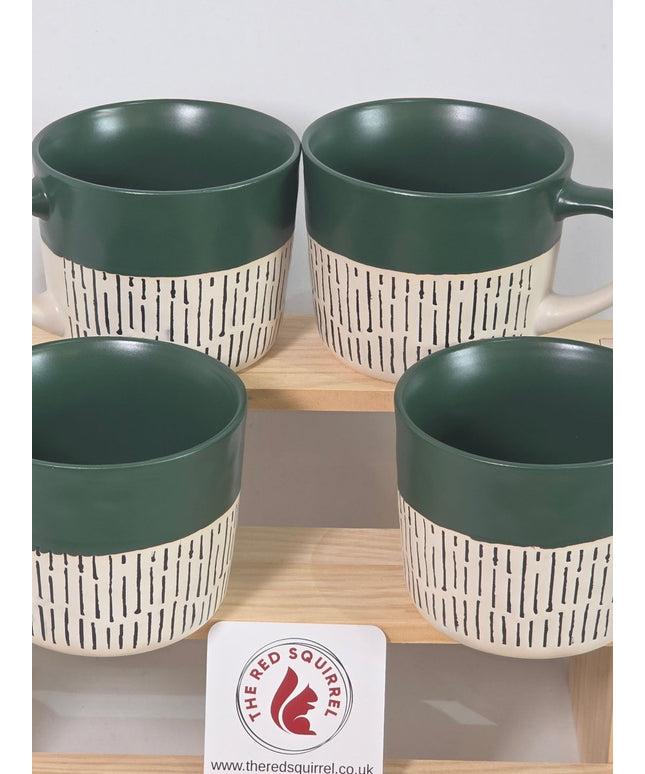 Four ceramic mugs with dark green interiors and handles, paired with cream-colored exteriors featuring a black dash pattern.