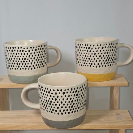 Three ceramic mugs with a black polka dot pattern on a cream body, 