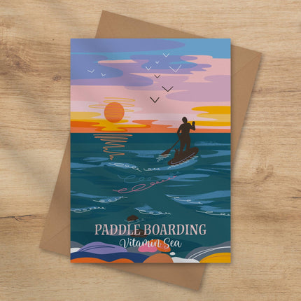 Greeting card with paddle boarding design on a wooden surface