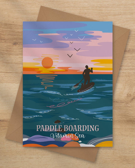 Greeting card with paddle boarding design on a wooden surface
