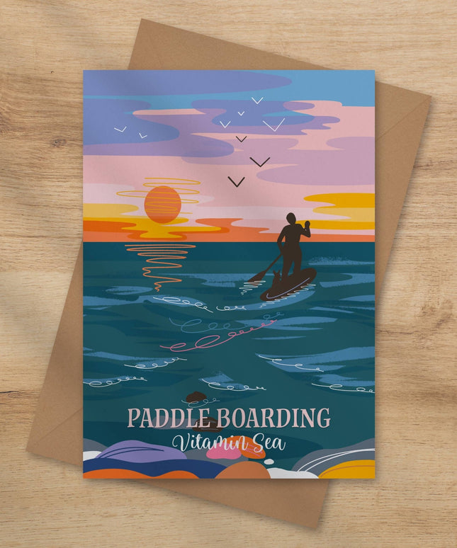 Greeting card with paddle boarding design on a wooden surface