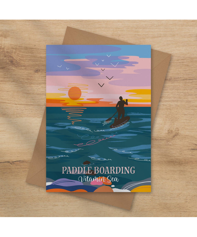 Greeting card with paddle boarding design on a wooden surface