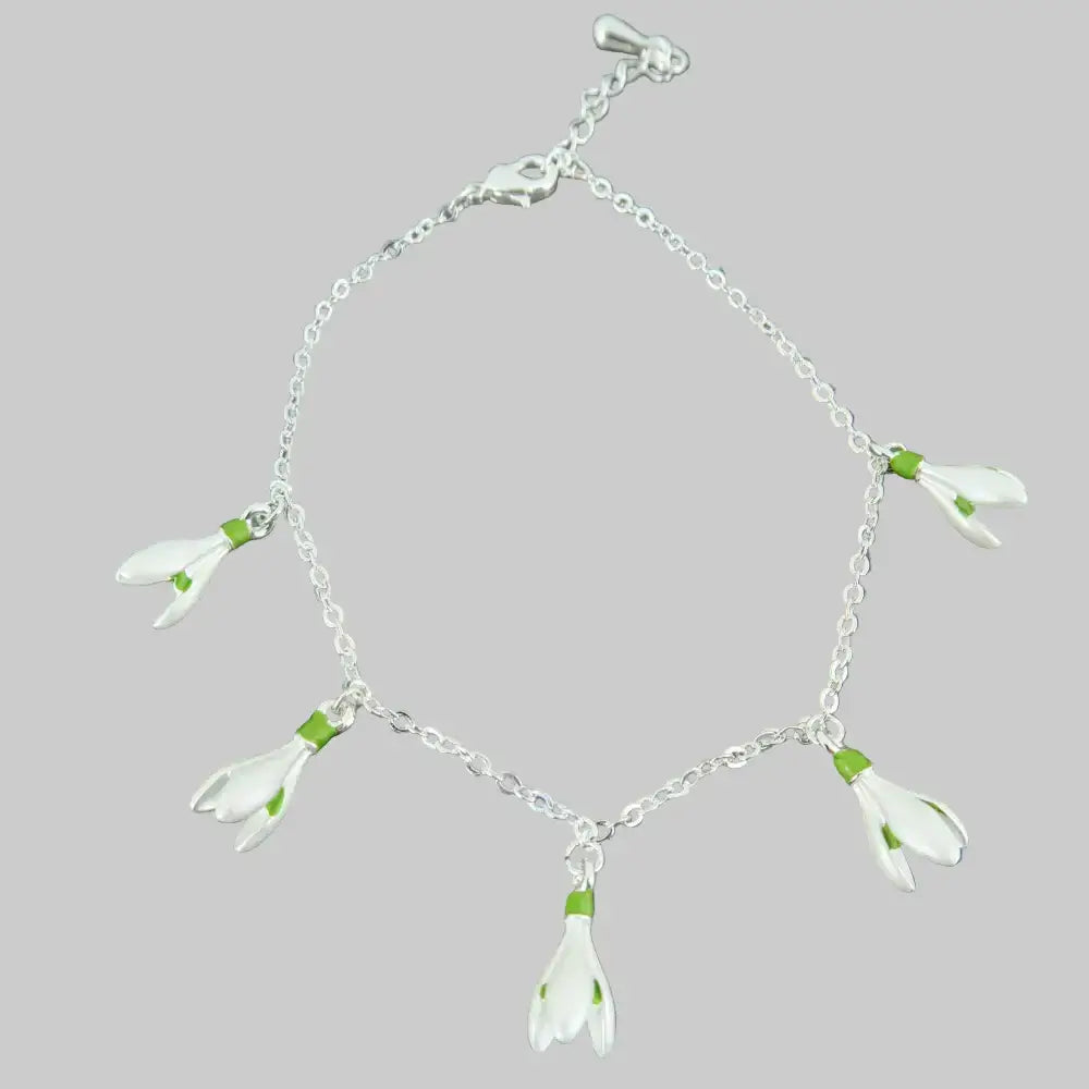 Silver bracelet with white flower charms on a stone background