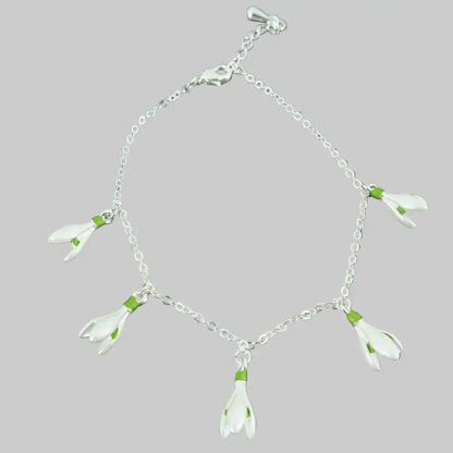 Silver bracelet with white flower charms on a stone background