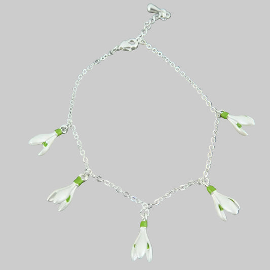 Silver bracelet with white flower charms on a stone background