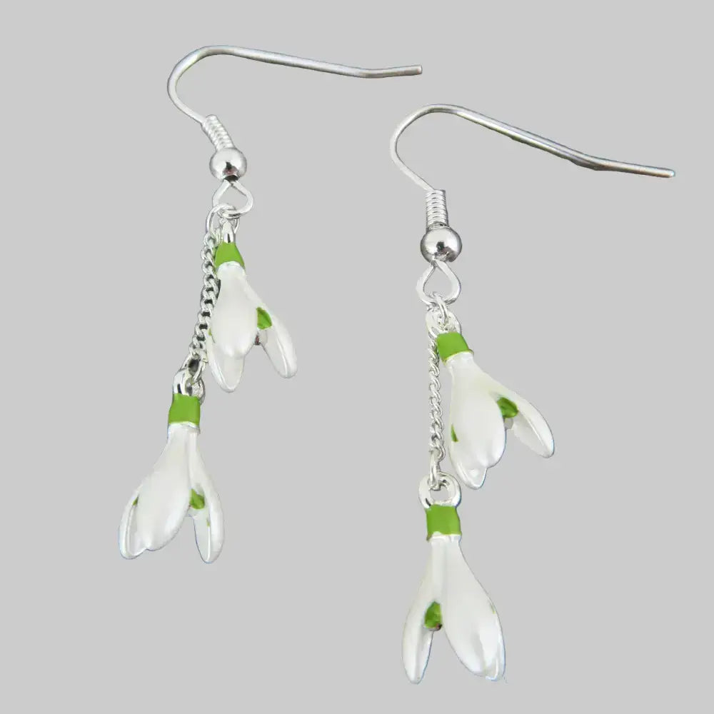 Silver earrings with white floral charms on a gray stone background