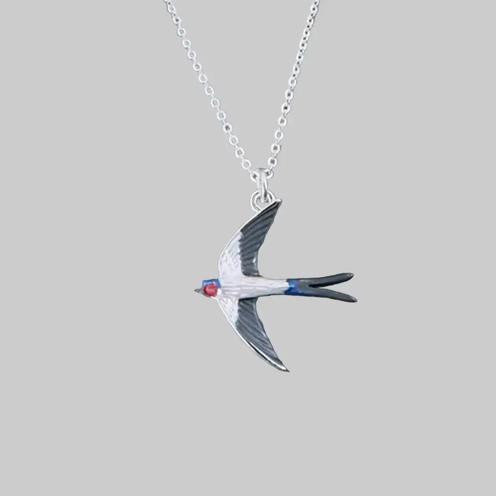 Silver swallow pendant necklace on a gray background