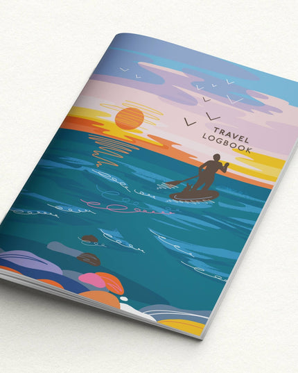 Notebook with a colorful design of a person paddleboarding at sunset, titled 'Travel Logbook'.