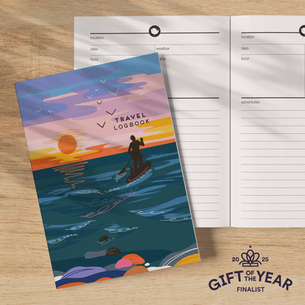 Travel logbook with a sunset design on a wooden surface