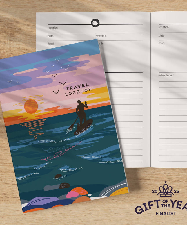 Travel logbook with a sunset design on a wooden surface
