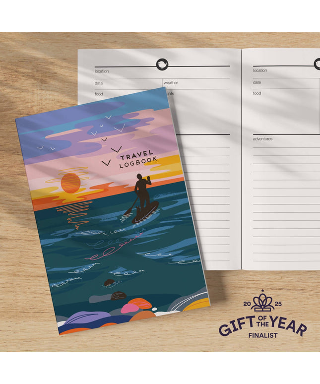 Travel logbook with a sunset design on a wooden surface