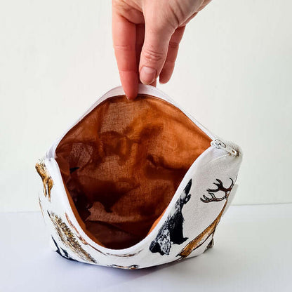 Hand holding a fabric pouch with animal prints on a white background