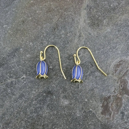Gold earrings with blue stones on a gray stone surface